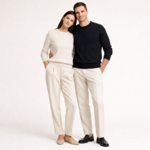 Un homme et une femme se tenant par les hanches posent pour une photo avec un fond unis. Ils portent tout deux le pull Boshu Merino de la marque HIKARI, l'homme porte la couleur noir encre et la femme la couleur ivoire.